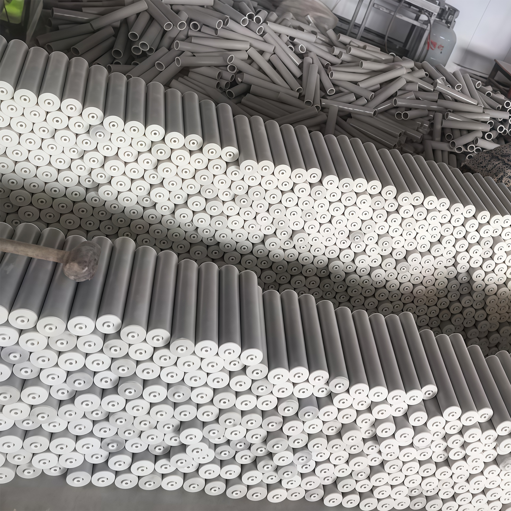 Rows of plastic rollers stacked end-on, with plastic tube stock behind